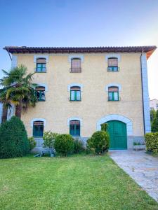 ein großes Haus mit grüner Tür und Hof in der Unterkunft Casa Rural Masión de Egüés in Elcano
