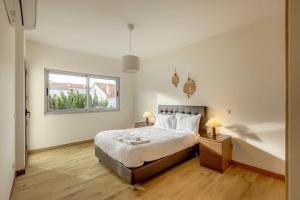 een slaapkamer met een bed en twee nachtkastjes met lampen bij Bright & Airy 3BR Spacious Villa in Sesimbra
