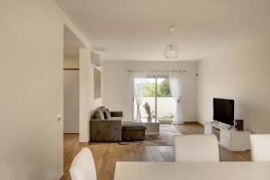 een witte woonkamer met een bank en een tv bij Bright & Airy 3BR Spacious Villa in Sesimbra