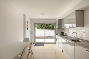 een keuken met witte kasten en een aanrecht met een wastafel bij Bright & Airy 3BR Spacious Villa in Sesimbra