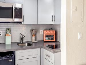 a kitchen with white cabinets and an orange microwave at Ocean Lodge in Boca Raton