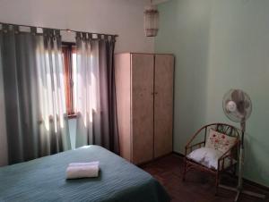 een slaapkamer met een bed, een stoel en een kast bij Casa de playa. Quequen in Quequén