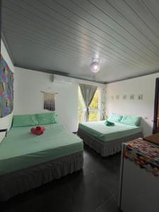 a bedroom with two beds and a window in it at Vila Pepouze Hostel in Morro de São Paulo