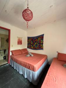 a bedroom with two beds and a chandelier at Vila Pepouze Hostel in Morro de São Paulo
