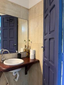 a bathroom with a sink and a blue door at Vila Pepouze Hostel in Morro de São Paulo