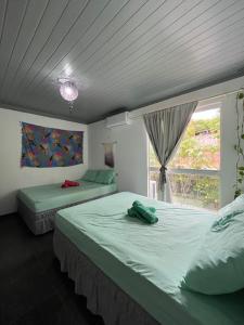 two beds in a room with a window at Vila Pepouze Hostel in Morro de São Paulo
