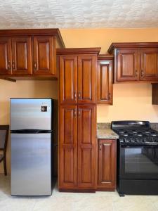 una cucina con mobili in legno e un frigorifero in acciaio inossidabile di Glenmuir Villa a May Pen