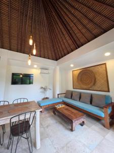 een woonkamer met een blauwe bank en een tafel bij Guava Garden in Gili Trawangan