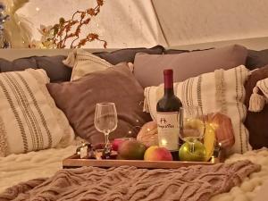 a tray of fruit and wine glasses on a bed at Paradise Gardens Glamping in Westville