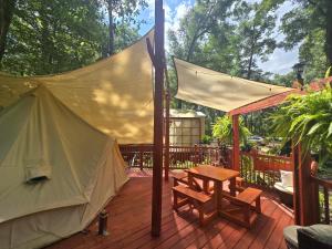 a tent on a wooden deck with a picnic table at Paradise Gardens Glamping in Westville