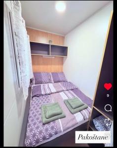 una piccola camera da letto con un letto viola con cuscini verdi di Laura, Milan a Pakoštane