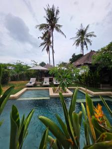 een zwembad in een resort met palmbomen bij Guava Garden in Gili Trawangan