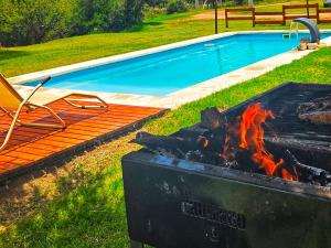 a barbecue next to a swimming pool with a chair and a chair at La Jocunda - Cortaderas - Piscu Yaco in Cortaderas +6 photos