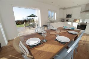 une table en bois avec des assiettes et des verres à vin dessus dans l'établissement 3 Bed in Gower oc-hh2105, à Rhossili