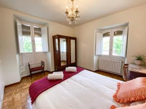 ein Schlafzimmer mit einem großen weißen Bett mit einem Kronleuchter in der Unterkunft Casa Rural Masión de Egüés in Elcano