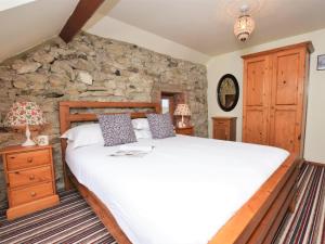 a bedroom with a large bed and a stone wall at 2 Bed in Godshill oc-ic072 in Godshill