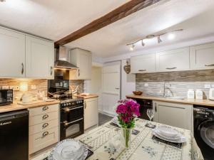 a kitchen with white cabinets and a table with flowers on it at 2 Bed in Ambleside oc-89748 in Hawkshead