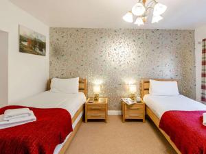 two beds in a small room with red sheets at 2 Bed in Ambleside oc-89748 in Hawkshead