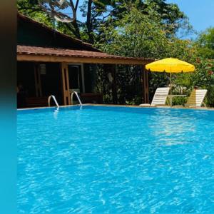 een groot blauw zwembad met een parasol bij Sítio Refúgio Primavera in Monte Verde