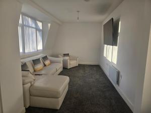 a white living room with a couch and two windows at 1 Bed City Centre Apartment in Derby