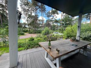 a wooden table on a porch with a view of a yard at Natuurhuisje Pine & Oak 6 persoons in Hardenberg