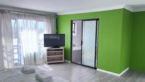 una stanza verde con una televisione e uno specchio di 3 Bed - Modern Retreat with Stay-in helper a Bloemfontein