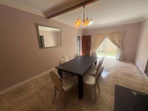 una sala da pranzo con tavolo e sedie neri di 3 Bed - Modern Retreat with Stay-in helper a Bloemfontein