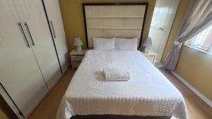 una camera da letto con un letto bianco con un asciugamano sopra di 3 Bed - Modern Retreat with Stay-in helper a Bloemfontein