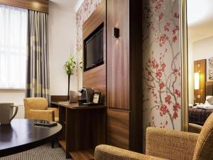 une chambre d'hôtel avec une table, des chaises et une télévision dans l'établissement Mercure Darlington King's Hotel, à Darlington