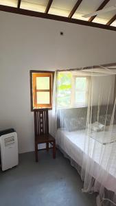 une chambre avec un lit, une chaise et une fenêtre dans l'établissement My House Ahangama, à Ahangama