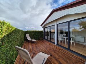 a wooden deck with white chairs and a table at Chalet 6 pers à 10km de Cabourg in Dozulé