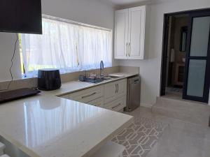 une cuisine avec des armoires blanches, un évier et une fenêtre dans l'établissement Cosy comfort, à George