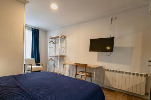 una camera con letto, scrivania e TV a parete di Albergue Miguel Ángel a Madrid