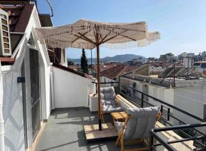 a patio with two chairs and an umbrella on a roof at Nodus Tollens Apart in Kaş