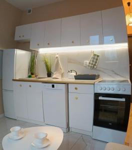 una cucina con armadietti bianchi, piano cottura e tavolo di Gold apartament a Poznań Altre 21 foto