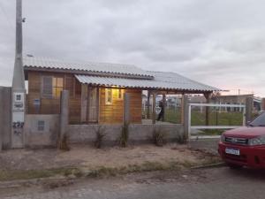 una piccola casa con un portico e una macchina rossa di Morada do Verão a Imbé