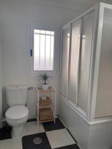 een witte badkamer met een toilet en een raam bij Apartamento Clavel in Chipiona