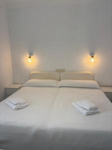 een wit bed met twee handdoeken erop bij Apartamento Clavel in Chipiona