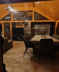 a dining room with a table and chairs and a couch at Greenhouse Klara with heated pool in Tršće