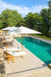 a pool with umbrellas and lounge chairs next to a swimming pool at Le domaine de rigou in Lasbordes