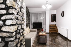 een woonkamer met een stenen muur en een bank bij Vilele Voineasa in Voineasa