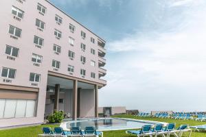 a hotel with chairs and a pool in front of a building at Hilton Garden Inn Veracruz Boca del Rio in Veracruz