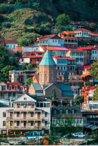 een groep gebouwen met een kerk op een heuvel bij Hotel Zaira in Tbilisi City