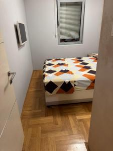a bedroom with a bed with a comforter and a window at Vila Ljubovic in Podgorica