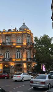 een gebouw met daarvoor geparkeerde auto's bij Hotel Zaira in Tbilisi City