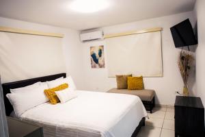 a bedroom with a large white bed with yellow pillows at Alojamiento completo familiar in Carolina