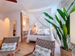 una camera con letto a baldacchino e 2 sedie di La Suite BALI, Charme et Confort, Hyper centre a La Roche-sur-Yon