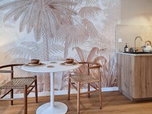 un tavolo e delle sedie in una cucina con carta da parati a forma di palma di La Suite BALI, Charme et Confort, Hyper centre a La Roche-sur-Yon
