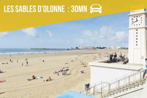 un gruppo di persone su una spiaggia con una torre dell'orologio di La Suite BALI, Charme et Confort, Hyper centre a La Roche-sur-Yon