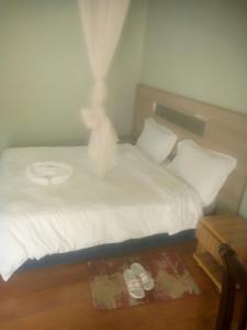 a bedroom with a white bed with a pair of slippers at Dagmaros in Bahir Dar